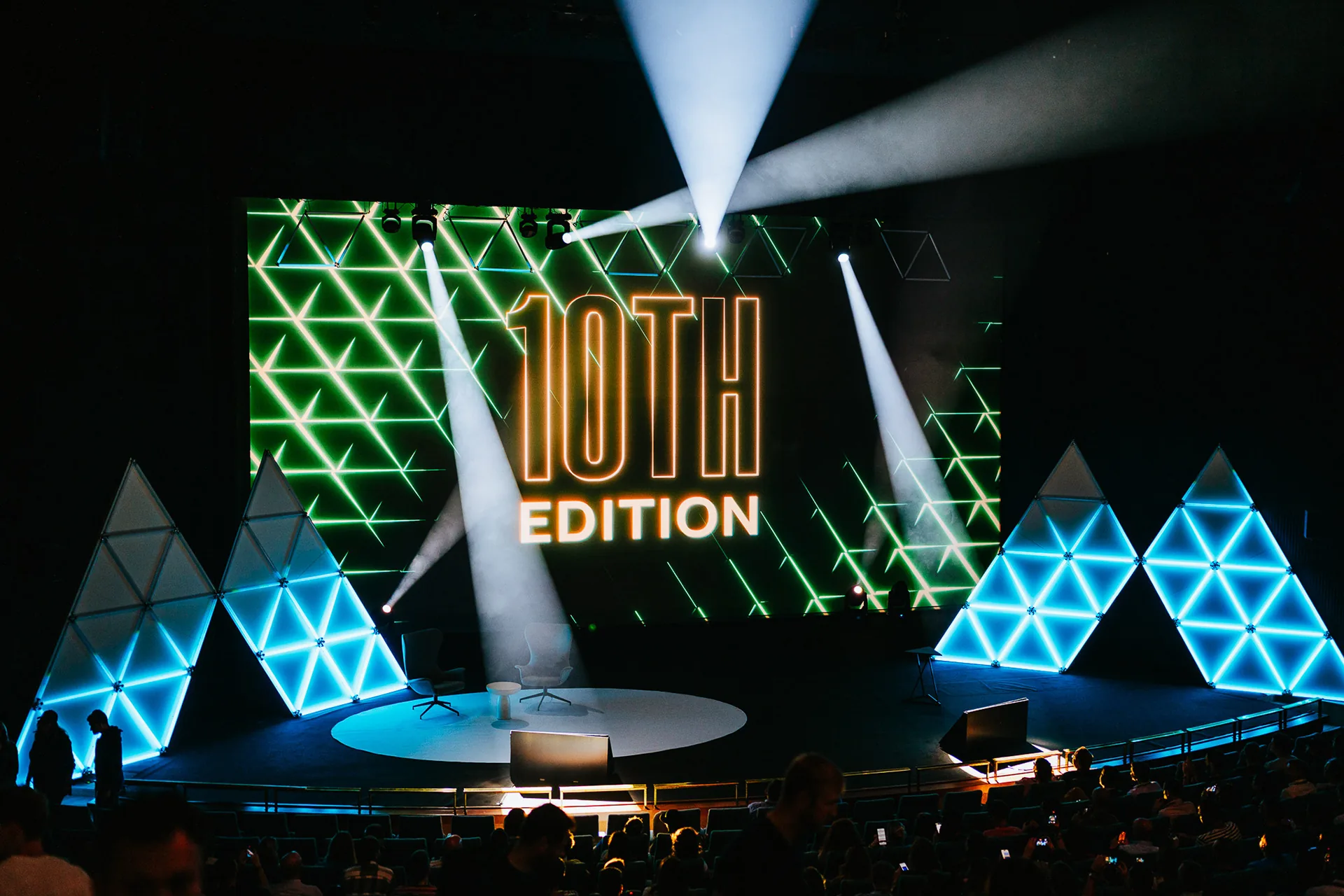Marketing Festival main stage with light beams and glowing triangle panels