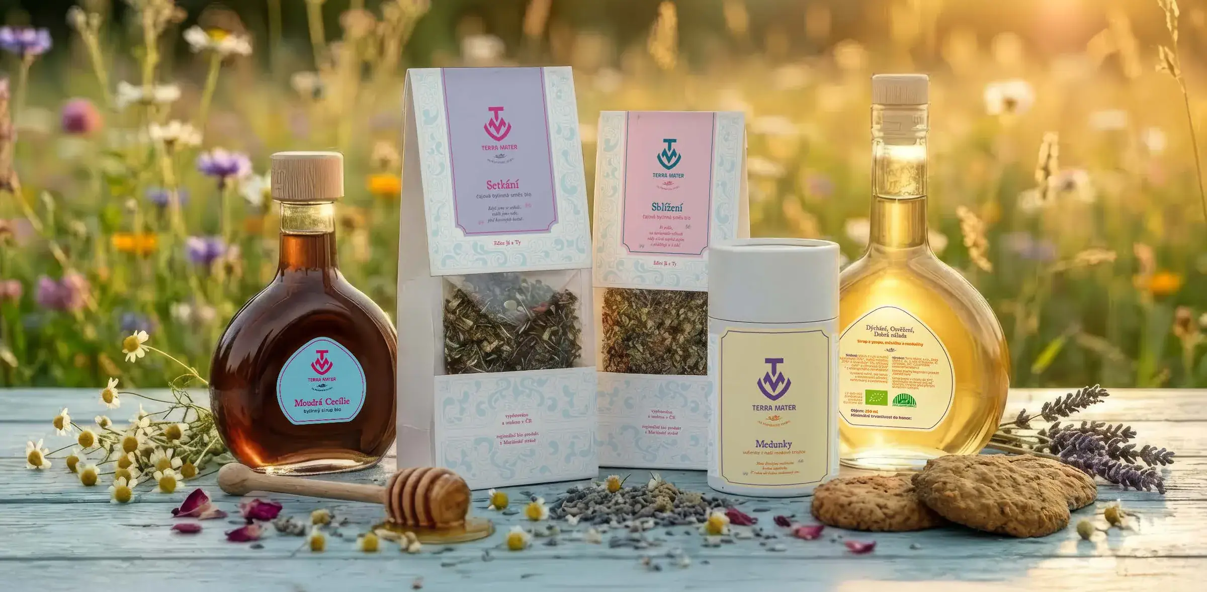 Terra Mater teas, syrups and cookies arranged on a table in a summer meadow